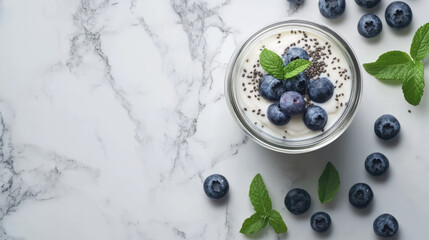 Homemade yogurt in glass jar topped with fresh blueberries and mint leaves, creating refreshing and healthy snack. Perfect for breakfast or dessert