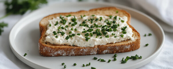 Whole grain toast topped with creamy spread and fresh chives, served on white plate. This healthy snack is perfect for breakfast or light meal
