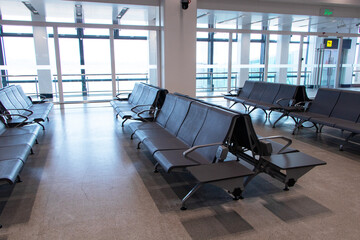 Empty Chairs brown for passengers waiting at airport lounge area station room. Modern design to serve public. Light shines through glass window. Modern interior design for tourists to travel around