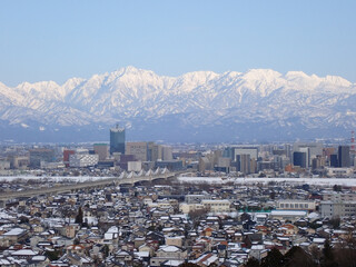 冠雪の北アルプス剱立山連峰と雪化粧の富山市街地