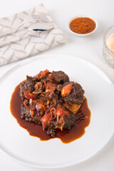 Indonesian sweet soy sauce grilled ribs, or Iga Bakar manis, cooked with chopped shallots and tomatoes

