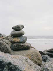Balanced stack of smooth rocks on ocean shore against cloudy sky