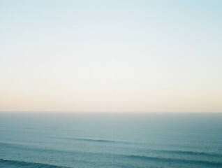 Obraz premium Calm ocean horizon at sunset with clear sky and gentle waves