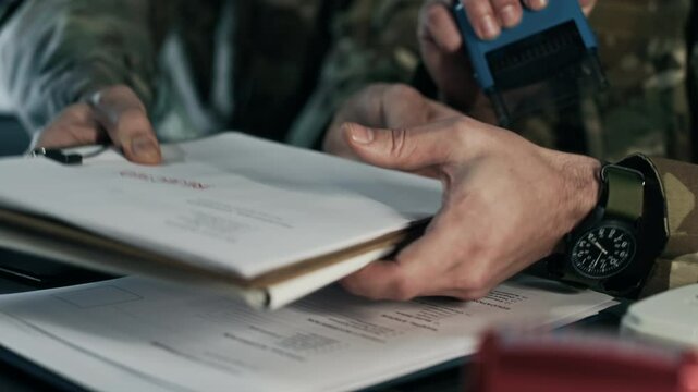 Cropped shot of hands of unrecognizable military workers preparing and stamping documents at desk in command center