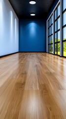 Modern open-space office interior with blue walls and wooden flooring featuring large windows for natural light