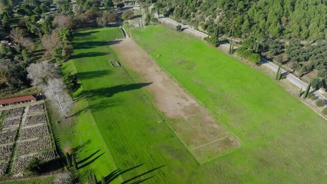 Slow drone reveal shot of ancient Olympia stadium in archaeological site of Ancient Olympia on a sunny day