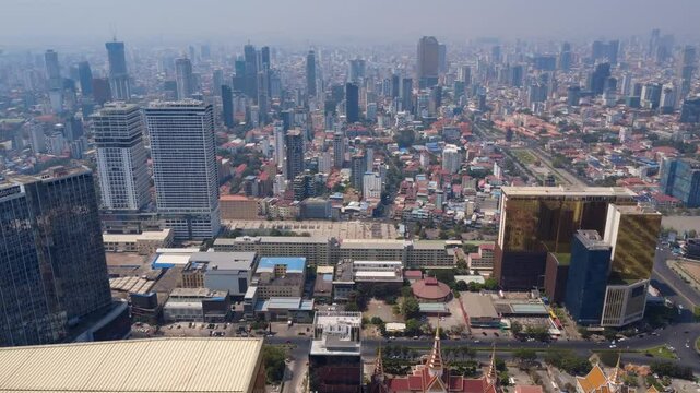 Phnom Penh city under hazy sky due to toxic air pollution with Preah Sihanouk boulevard and historical Independence Monument park on the right, Cambodia skylines, Drone shot