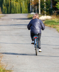 Obraz premium A woman is riding a bicycle down a road