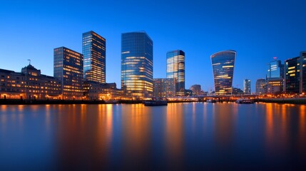 Fototapeta premium Stunning city skyline at dusk with illuminated buildings reflecting in the calm water