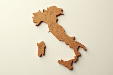 Fototapeta premium A rustic, handcrafted cork map of a boot-shaped peninsula, meticulously detailed with natural fissures and a warm, earthy tone, rests gently on a smooth, off-white surface.