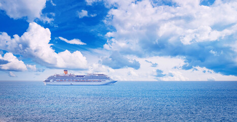 Majestic cruise ship sailing under a vast blue sky with puffy clouds