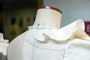 A dressmaker’s mannequin with pinned fabric in a fashion design school or small business studio....