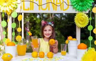 Cute girl makes delicious lemonade on the street in the park
