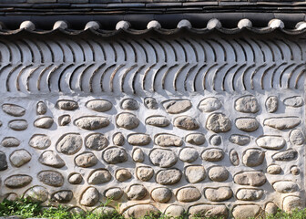 Oriental decorative wall of traditional Korean house with roof tile. Oriental horizontal background with old stone fence, South Korea