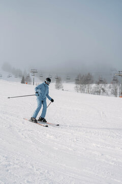 A girl in a blue ski suit is sliding down a slope