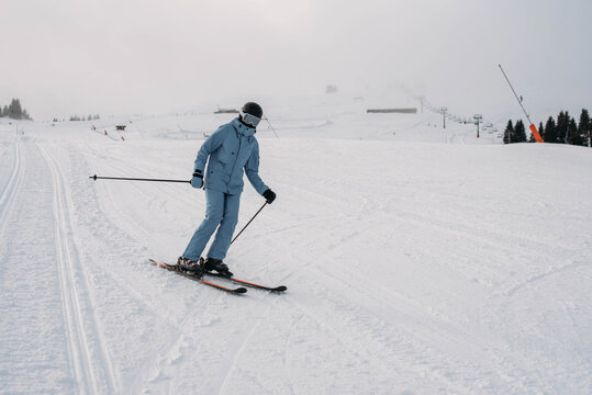 A girl in a blue ski suit sliding down a snowy slope