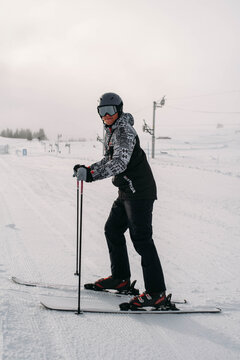 Smiling skier standing on slope and looking at camera