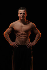 Fototapeta premium Adult male athlete bodybuilder posing on a orange light