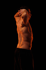 Fototapeta premium Adult male athlete bodybuilder posing on a orange light