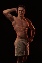 Adult male athlete bodybuilder posing on a orange light