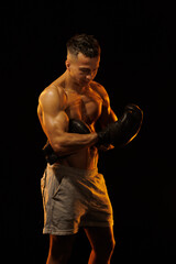 Adult male athlete bodybuilder posing on a orange light	
