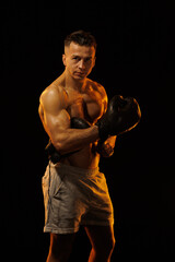 Adult male athlete bodybuilder posing on a orange light	