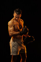 Adult male athlete bodybuilder posing on a orange light	