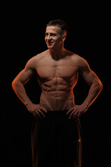 Fototapeta premium Adult male athlete bodybuilder posing on a orange light 