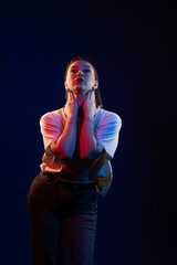 Young girl posing and moving in a black studio with colored light