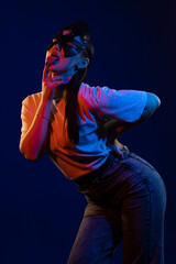 Young girl posing and moving in a black studio with colored light	