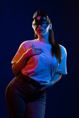 Young girl posing and moving in a black studio with colored light	