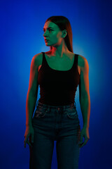 Young girl posing and moving in a black studio with colored light	