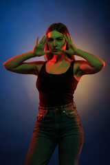 Young girl posing and moving in a black studio with colored light	