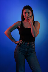 Young girl posing and moving in a black studio with colored light	