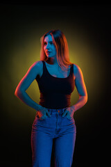 Young girl posing and moving in a black studio with colored light	
