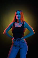 Young girl posing and moving in a black studio with colored light	