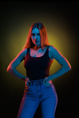 Young girl posing and moving in a black studio with colored light	