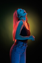 Young girl posing and moving in a black studio with colored light	