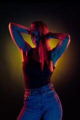 Young girl posing and moving in a black studio with colored light