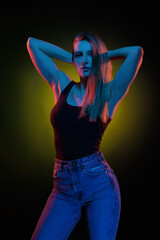 Young girl posing and moving in a black studio with colored light	