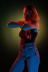 Young girl posing and moving in a black studio with colored light