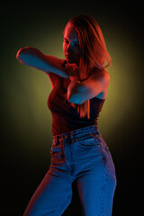 Young girl posing and moving in a black studio with colored light