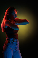 Young girl posing and moving in a black studio with colored light