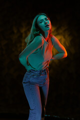 Young girl posing and moving in a black studio with colored light