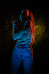 Young girl posing and moving in a black studio with colored light	