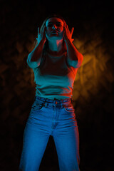 Young girl posing and moving in a black studio with colored light	