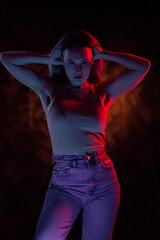 Young girl posing and moving in a black studio with colored light	