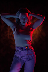 Young girl posing and moving in a black studio with colored light	