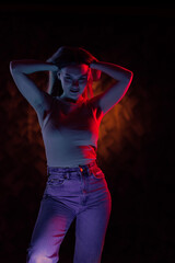 Young girl posing and moving in a black studio with colored light	