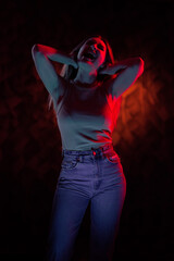 Young girl posing and moving in a black studio with colored light	
